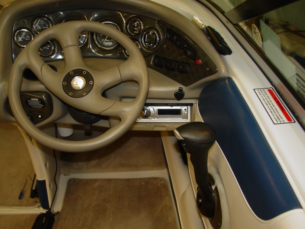 The steering wheel of a boat with a radio installed in the dashboard