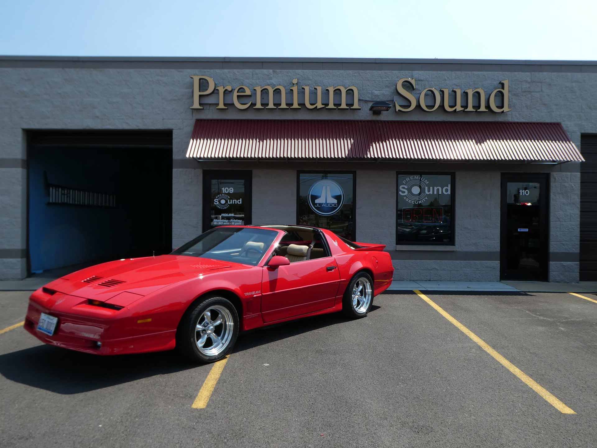 Premium Sound & Security storefront with a red sports car parked in front