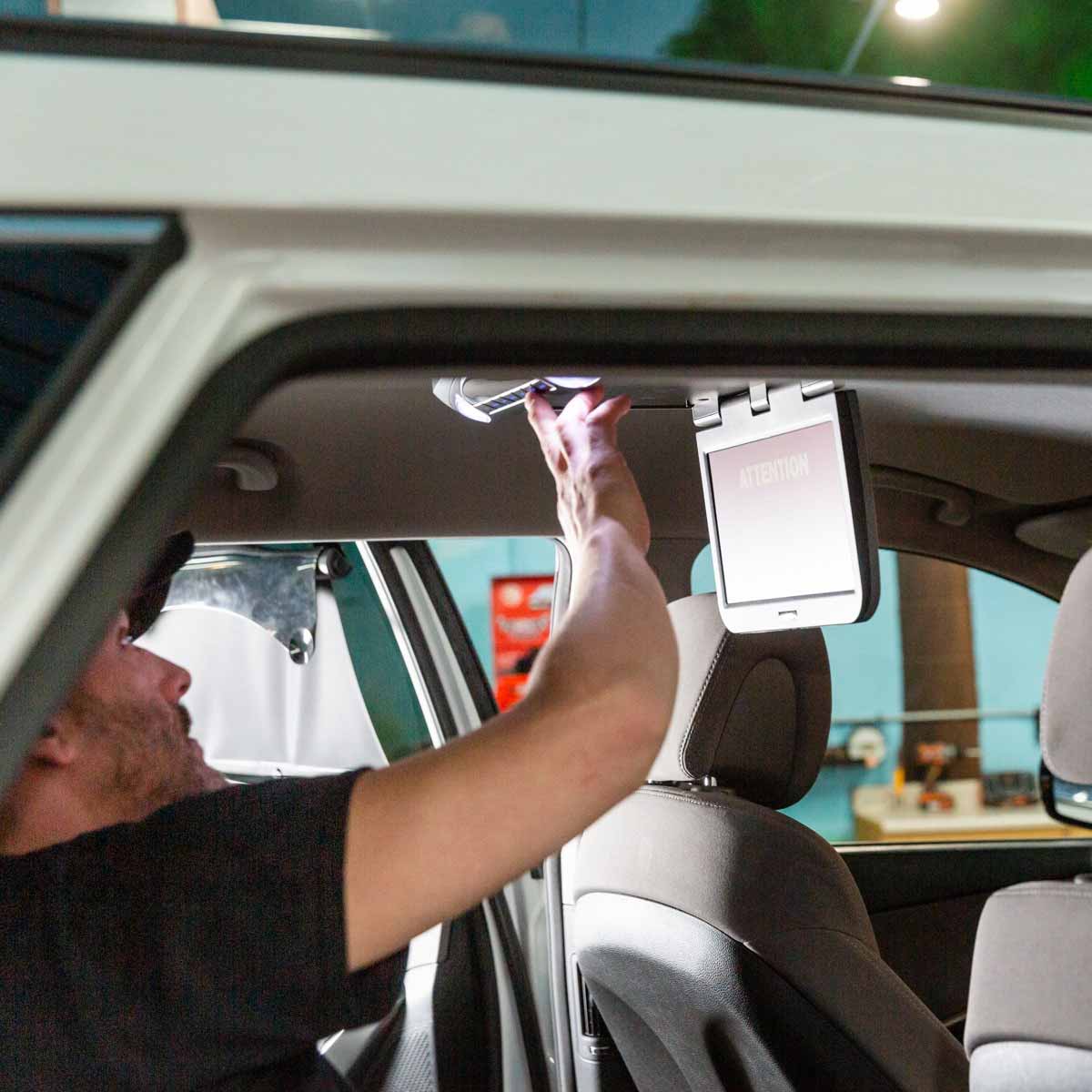 A man installing a mobile video player in the back of a car