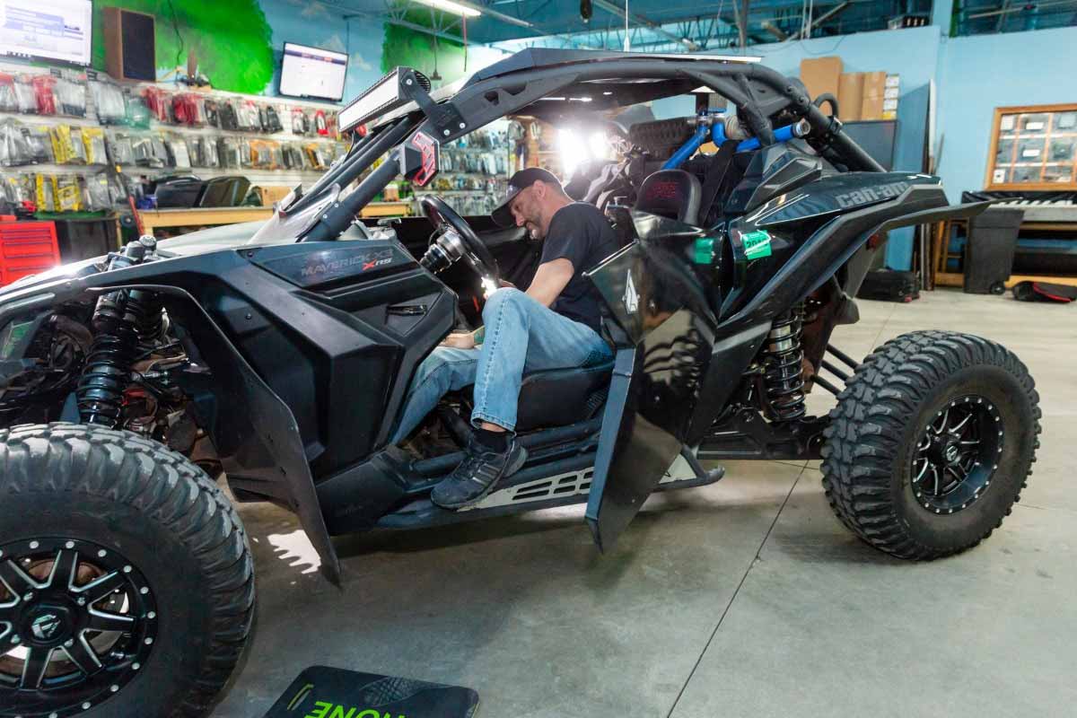 A man installing a new speaker system in a dune buggy